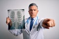 Middle age handsome grey-haired doctor man holding chest xray over white background pointing with finger to the camera and to you, Royalty Free Stock Photo