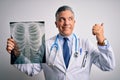 Middle age handsome grey-haired doctor man holding chest xray over white background pointing and showing with thumb up to the side Royalty Free Stock Photo