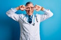 Middle age handsome grey-haired doctor man wearing coat and blue stethoscope Doing peace symbol with fingers over face, smiling Royalty Free Stock Photo