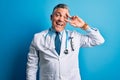 Middle age handsome grey-haired doctor man wearing coat and blue stethoscope Doing peace symbol with fingers over face, smiling Royalty Free Stock Photo