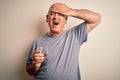 Middle age handsome hoary man drinking glass of water over isolated white background stressed with hand on head, shocked with