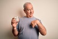 Middle age handsome hoary man drinking glass of water over isolated white background with surprise face pointing finger to himself