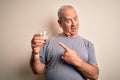 Middle age handsome hoary man drinking glass of water over isolated white background very happy pointing with hand and finger