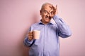 Middle age handsome hoary man drinking mug of coffee over isolated pink background with happy face smiling doing ok sign with hand