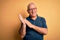 Middle age handsome hoary man wearing casual polo and glasses over yellow background clapping and applauding happy and joyful,