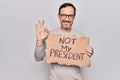 Middle age handsome man on disagreement holding banner with not my president message doing ok sign with fingers, smiling friendly Royalty Free Stock Photo