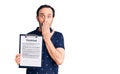 Middle age handsome man holding clipboard with contract document covering mouth with hand, shocked and afraid for mistake