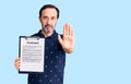 Middle age handsome man holding clipboard with contract document with open hand doing stop sign with serious and confident