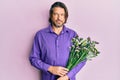 Middle age handsome man holding flowers thinking attitude and sober expression looking self confident