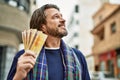 Middle age handsome man holding norwegian krone banknotes at the town Royalty Free Stock Photo