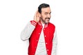 Middle age handsome man wearing baseball jacket over isolated white background smiling with hand over ear listening and hearing to Royalty Free Stock Photo
