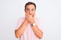 Middle age handsome man wearing casual pink shirt standing over isolated white background shocked covering mouth with hands for Royalty Free Stock Photo