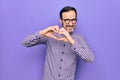 Middle age handsome man wearing casual shirt and glasses over isolated white background smiling in love doing heart symbol shape Royalty Free Stock Photo