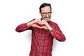 Middle age handsome man wearing casual shirt and glasses over isolated white background smiling in love doing heart symbol shape Royalty Free Stock Photo