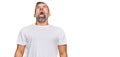 Middle age handsome man wearing casual white tshirt angry and mad screaming frustrated and furious, shouting with anger Royalty Free Stock Photo