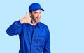 Middle age handsome man wearing mechanic uniform smiling doing phone gesture with hand and fingers like talking on the telephone Royalty Free Stock Photo
