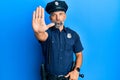 Middle age handsome man wearing police uniform doing stop sing with palm of the hand