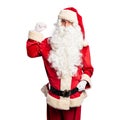 Middle age handsome man wearing Santa Claus costume and beard standing Strong person showing arm muscle, confident and proud of Royalty Free Stock Photo