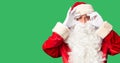 Middle age handsome man wearing Santa Claus costume and beard standing Trying to open eyes with fingers, sleepy and tired for Royalty Free Stock Photo