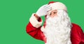 Middle age handsome man wearing Santa Claus costume and beard standing very happy and smiling looking far away with hand over head Royalty Free Stock Photo