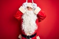 Middle age handsome man wearing Santa costume standing over isolated red background doing funny gesture with finger over head as Royalty Free Stock Photo