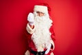 Middle age handsome man wearing Santa costume standing over isolated red background Doing Italian gesture with hand and fingers Royalty Free Stock Photo