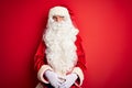 Middle age handsome man wearing Santa costume standing over isolated red background looking sleepy and tired, exhausted for Royalty Free Stock Photo