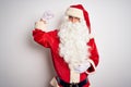 Middle age handsome man wearing Santa costume standing over isolated white background Strong person showing arm muscle, confident Royalty Free Stock Photo