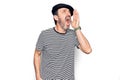 Middle age handsome man wearing striped t-shirt and french beret over white background shouting and screaming loud to side with