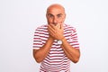 Middle age handsome man wearing striped t-shirt standing over isolated white background shocked covering mouth with hands for Royalty Free Stock Photo