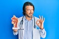 Middle age handsome otologist doctor man holding medical model doing ok sign with fingers, smiling friendly gesturing excellent