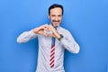 Middle age handsome patriotic businessman wearing united states tie over blue background smiling in love doing heart symbol shape