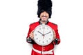 Middle age handsome wales guard man wearing traditional uniform holding big clock looking positive and happy standing and smiling