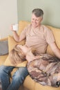 middle age happy couple relaxing at home on a sofa with tea cup. woman looking at man unwards. smiling family aged 50 Royalty Free Stock Photo