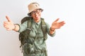 Middle age hiker woman wearing backpack canteen hat glasses over isolated white background looking at the camera smiling with open Royalty Free Stock Photo