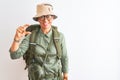 Middle age hiker woman wearing backpack canteen hat glasses over isolated white background smiling and confident gesturing with Royalty Free Stock Photo