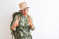 Middle age hiker woman wearing backpack canteen hat glasses over isolated white background smiling looking to the camera showing Royalty Free Stock Photo