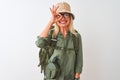 Middle age hiker woman wearing backpack hat canteen glasses over isolated white background doing ok gesture with hand smiling, eye Royalty Free Stock Photo