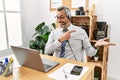 Middle age hispanic business man working at the office wearing operator headset amazed and smiling to the camera while presenting Royalty Free Stock Photo