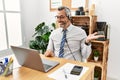 Middle age hispanic business man working at the office wearing operator headset smiling cheerful presenting and pointing with palm Royalty Free Stock Photo