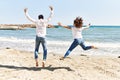 Middle age hispanic couple on back view jumping at the beach