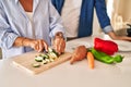 Middle age hispanic couple cutting zucchini at kitchen