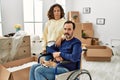Middle age hispanic couple and dog sitting on wheelchair at new home thinking attitude and sober expression looking self confident Royalty Free Stock Photo