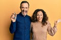 Middle age hispanic couple holding keys of new home celebrating victory with happy smile and winner expression with raised hands Royalty Free Stock Photo