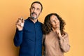 Middle age hispanic couple holding keys of new home serious face thinking about question with hand on chin, thoughtful about Royalty Free Stock Photo