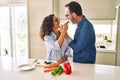 Middle age hispanic couple smiling confident eating zucchini at kitchen Royalty Free Stock Photo