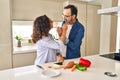 Middle age hispanic couple smiling confident eating zucchini at kitchen Royalty Free Stock Photo