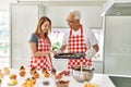 Middle age hispanic couple smiling happy baking cookies at the kitchen Royalty Free Stock Photo