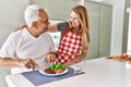 Middle age hispanic couple smiling happy eating beef with salad at the kitchen Royalty Free Stock Photo