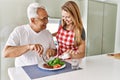 Middle age hispanic couple smiling happy eating beef with salad at the kitchen Royalty Free Stock Photo